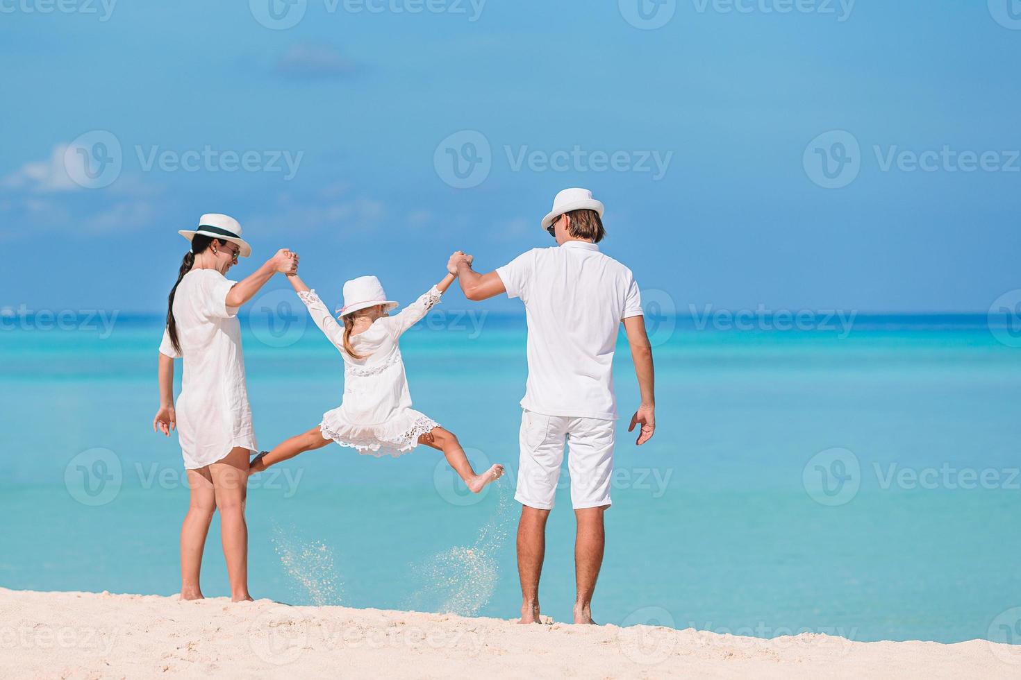 Lycklig familj av tre har roligt tillsammans på de strand foto