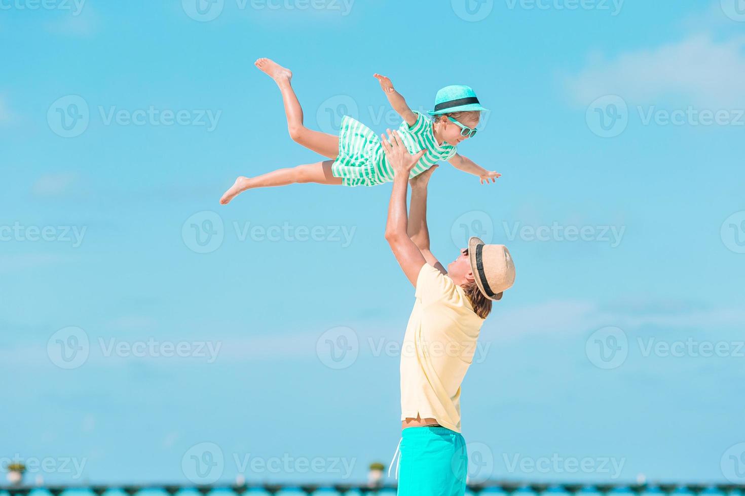 liten flicka och Lycklig pappa har roligt under strand semester foto