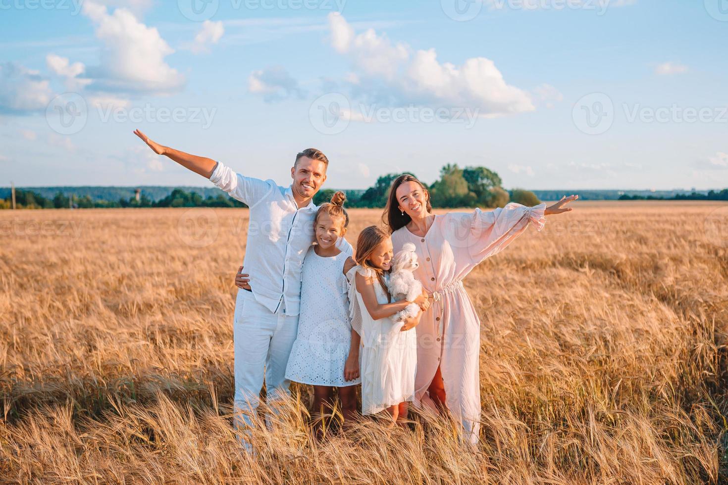 Lycklig familj spelar i en vete fält foto