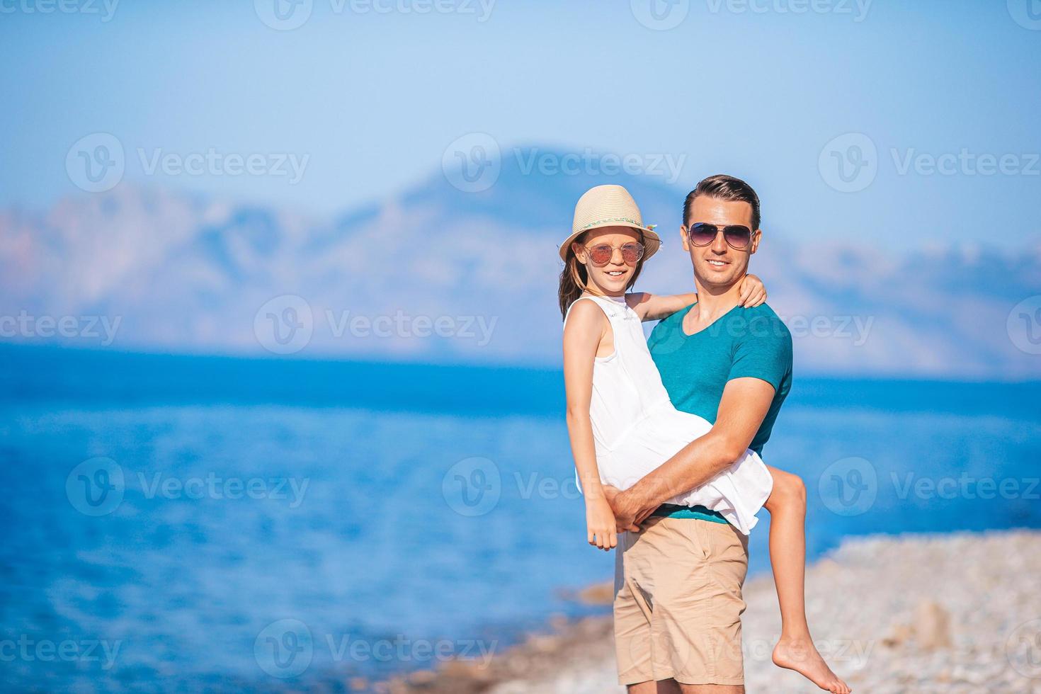 liten flicka och Lycklig pappa har roligt under strand semester foto