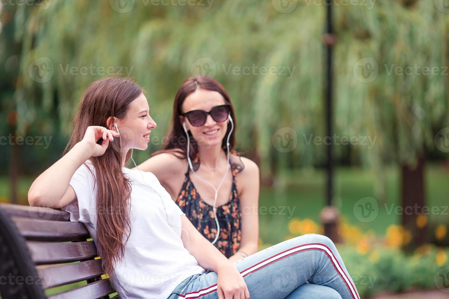 bäst vänner Sammanträde på en bänk i en sommar parkera foto