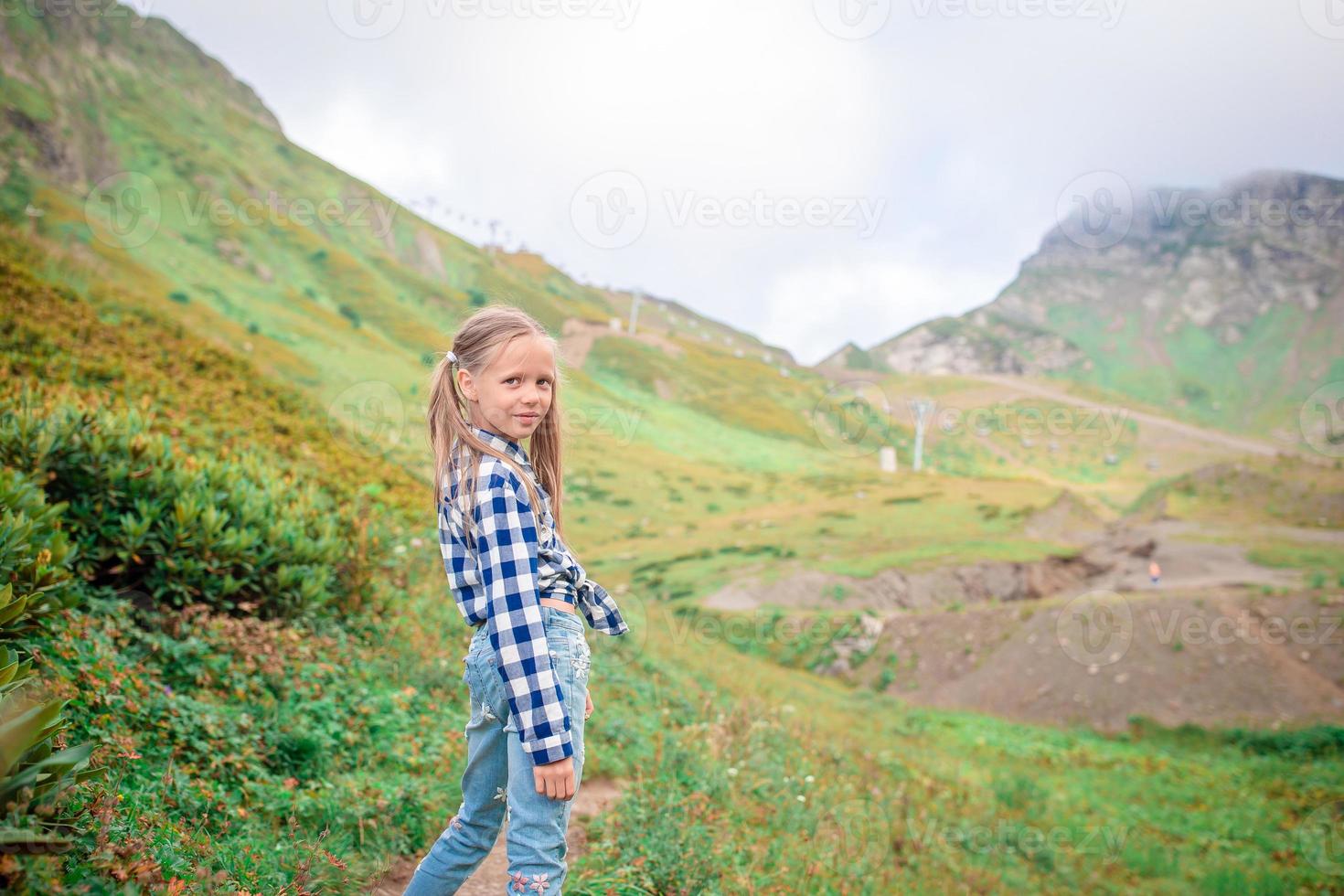 skön Lycklig liten flicka i bergen i de bakgrund av dimma foto