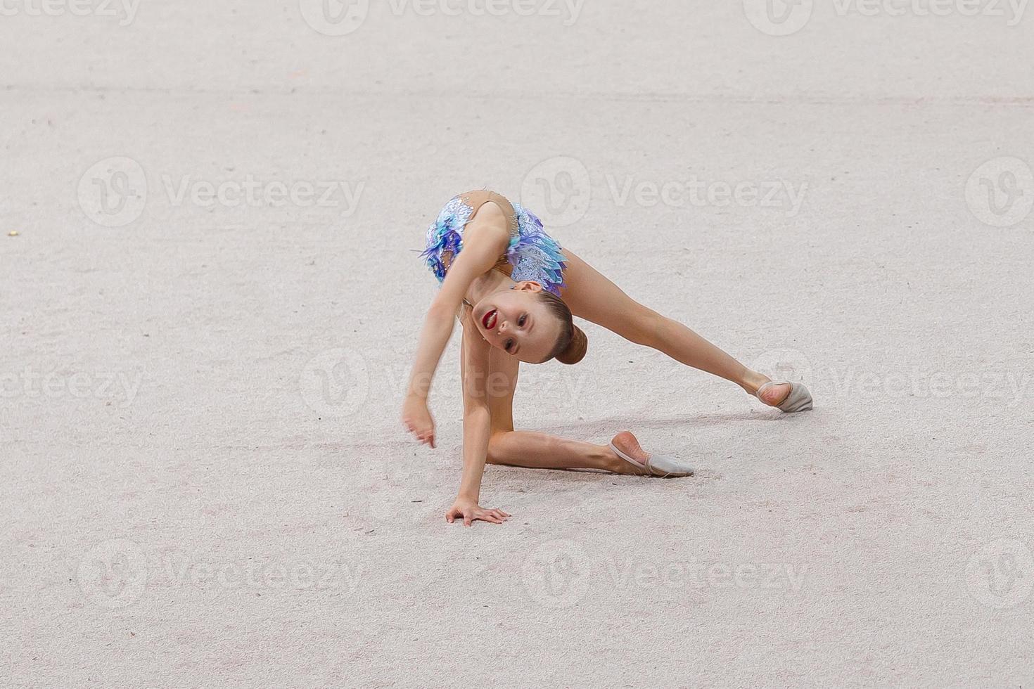 skön liten aktiva gymnast flicka med henne prestanda på de matta foto