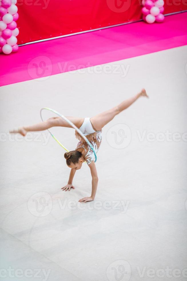 liten gymnast Träning på de matta och redo för tävlingar foto