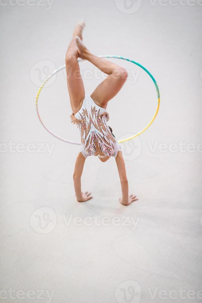 liten gymnast Träning på de matta och redo för tävlingar foto