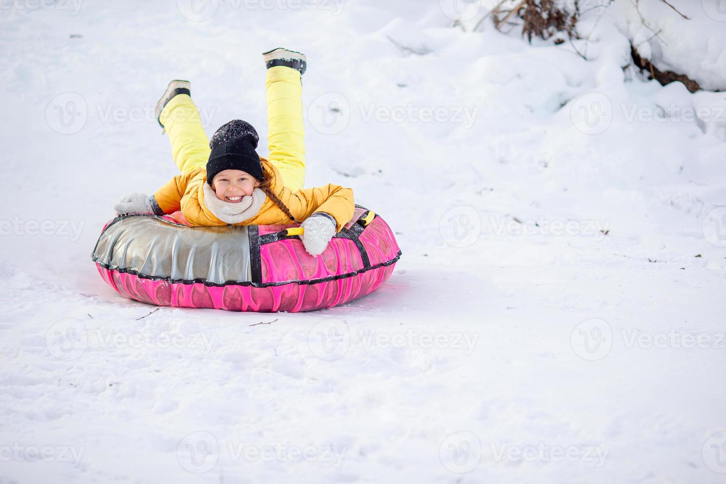 förtjusande liten Lycklig flicka sledding i vinter- snöig dag. foto