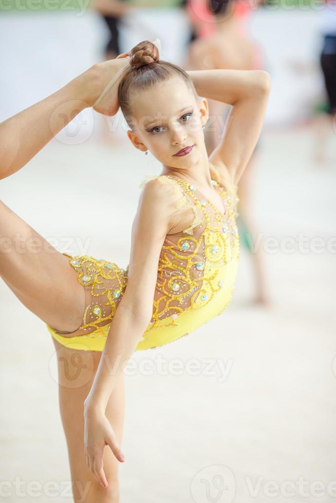 skön liten aktiva gymnast flicka med henne prestanda på de matta foto