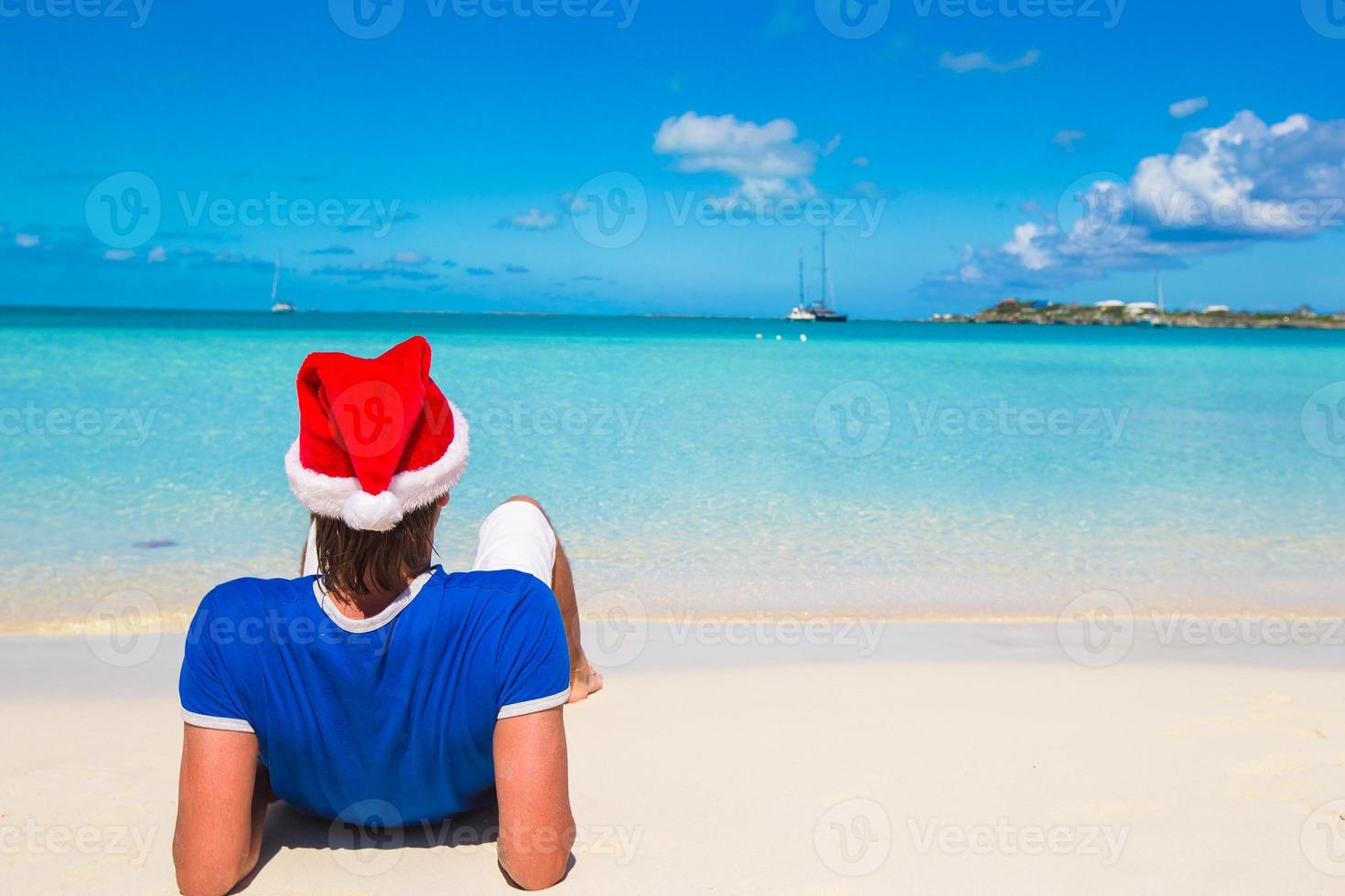 ung man i santa hatt på tropisk strand foto