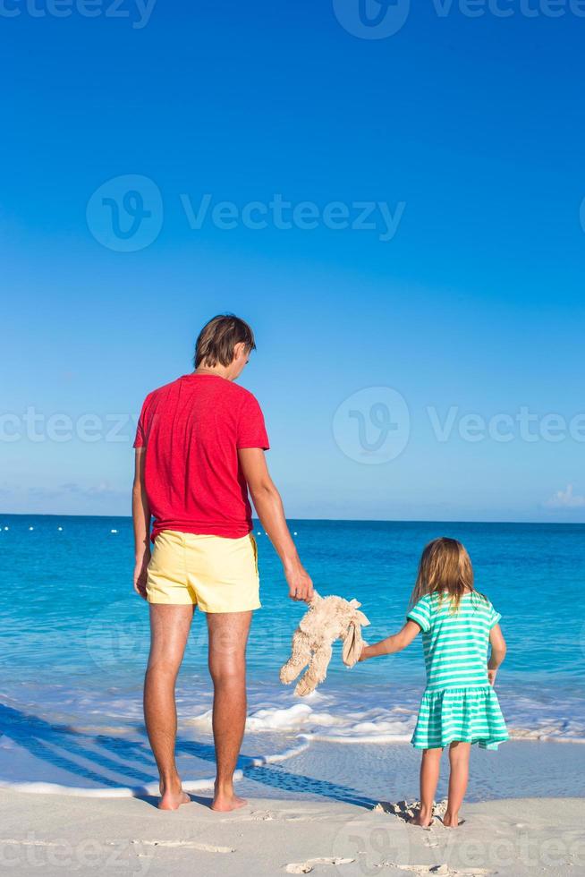 pappa med liten dotter innehav kanin leksak på karibiska strand foto