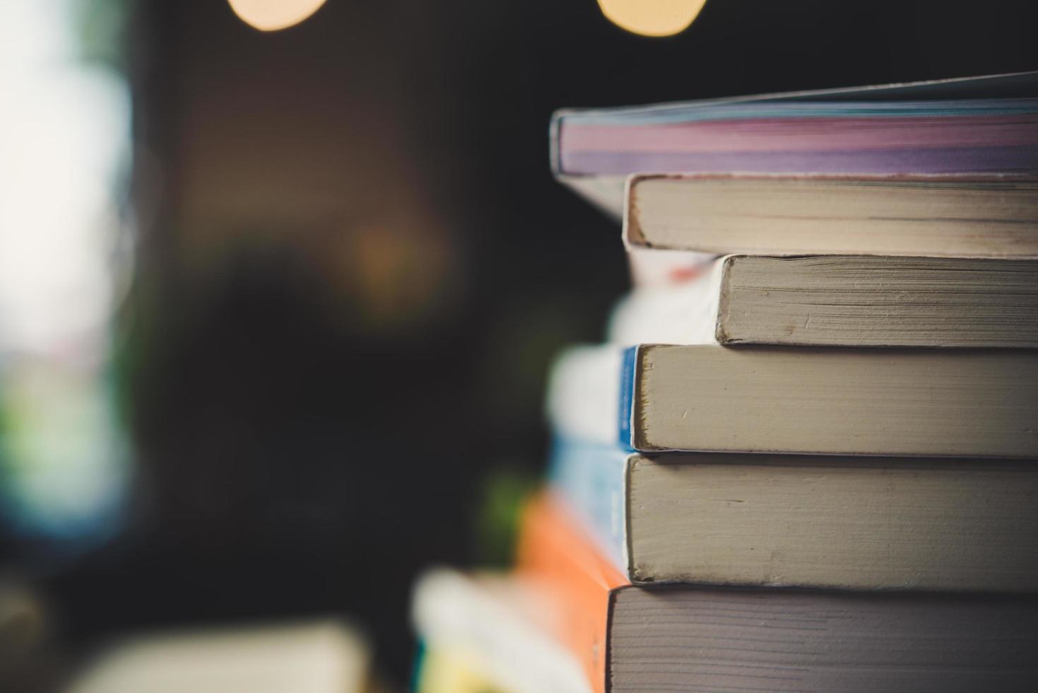 högar med böcker på ett bord över en suddig biblioteksbakgrund foto