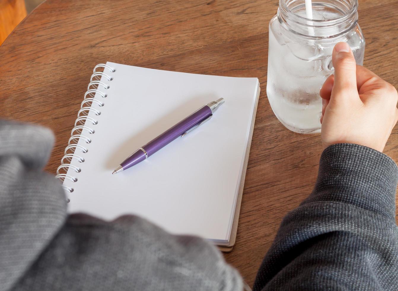 anteckningsbok och penna med ett glas vatten på ett bord foto