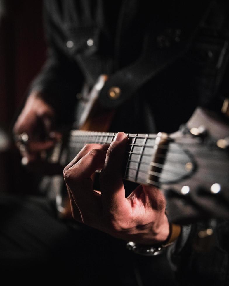 man som spelar gitarr i närbildfotografering foto