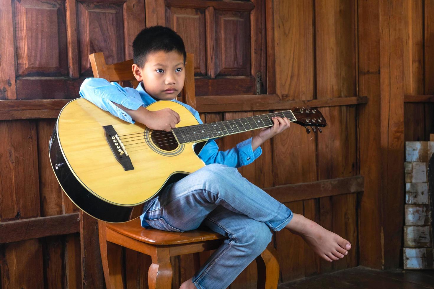pojke som spelar en akustisk gitarr foto