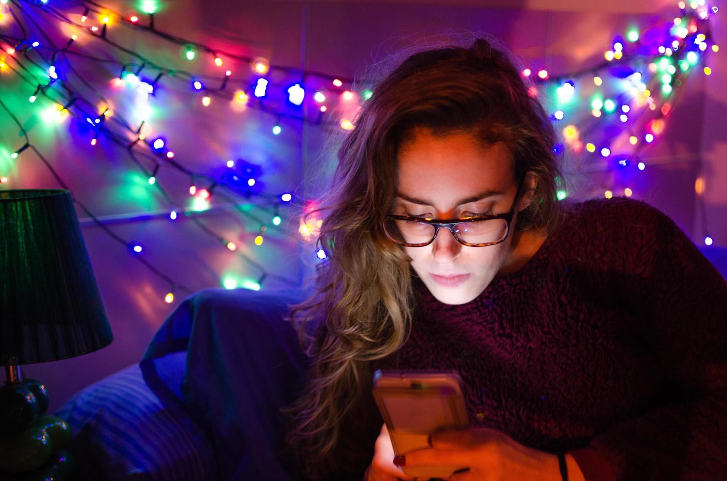 blond tjej som leker på sin telefon i hennes rum foto