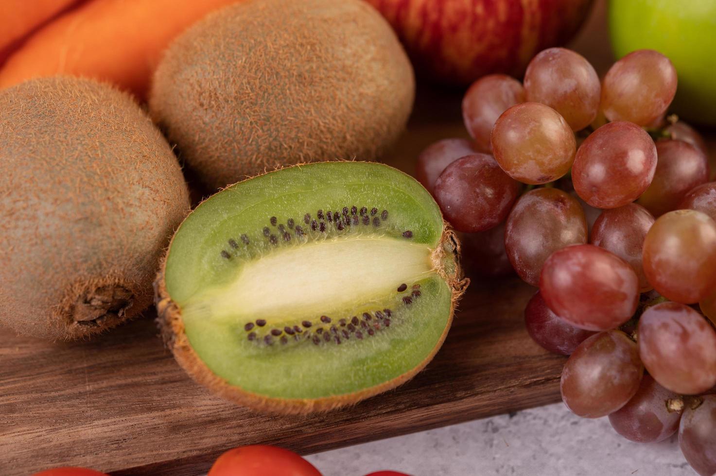 närbild av kiwi, druvor, äpplen, med morötter foto