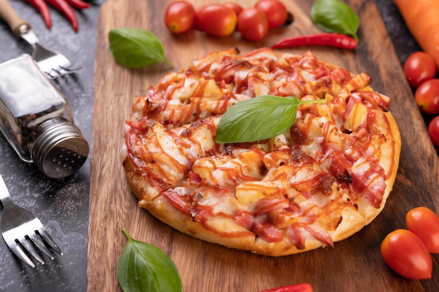 hemlagad pizza på en träbricka med tomater och chili foto