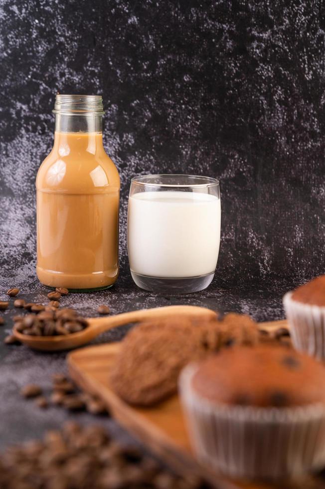 kaffe och mjölk med muffins och kaffebönor i förgrunden foto