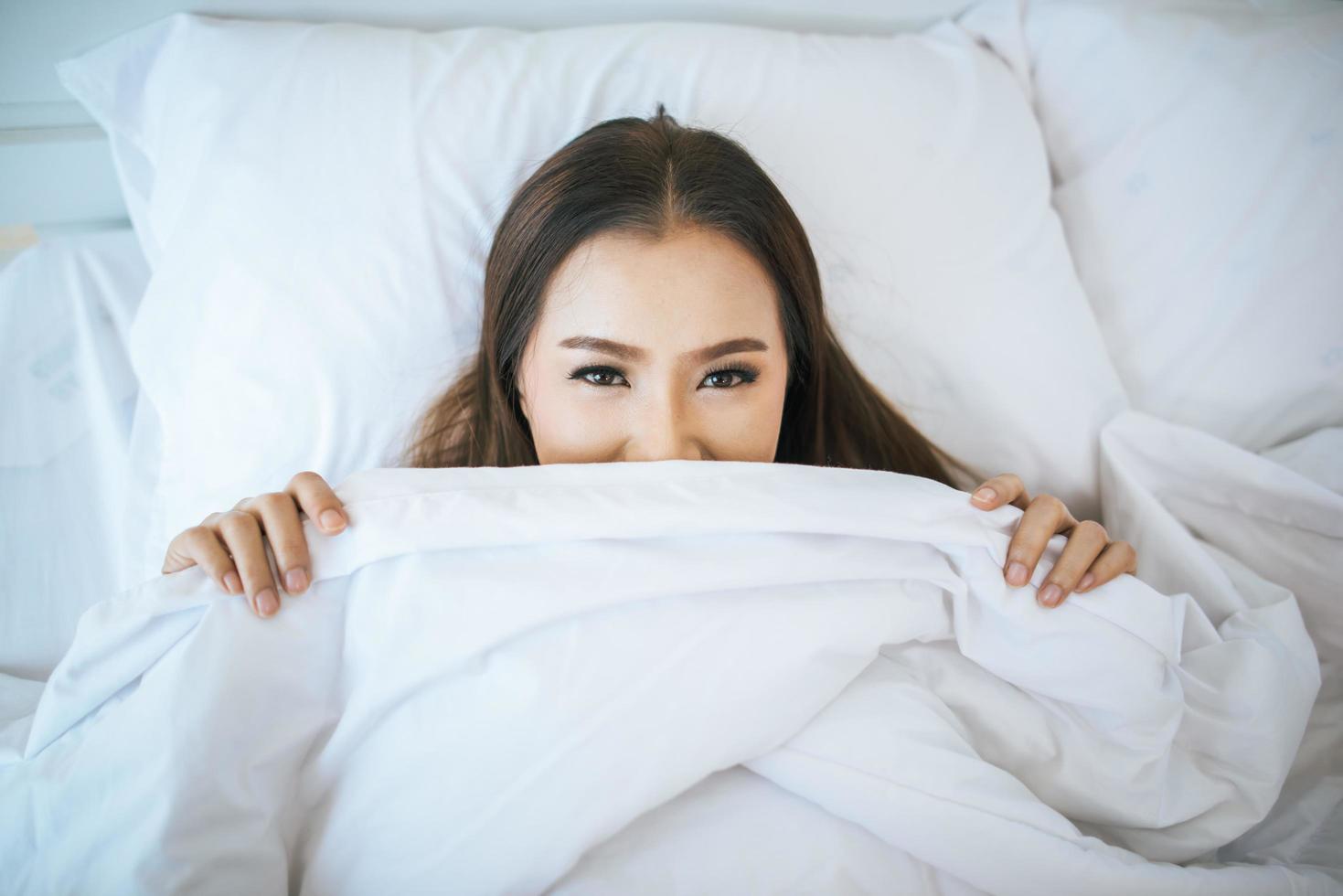 kvinna som vaknar i sin säng, lat på morgonen foto