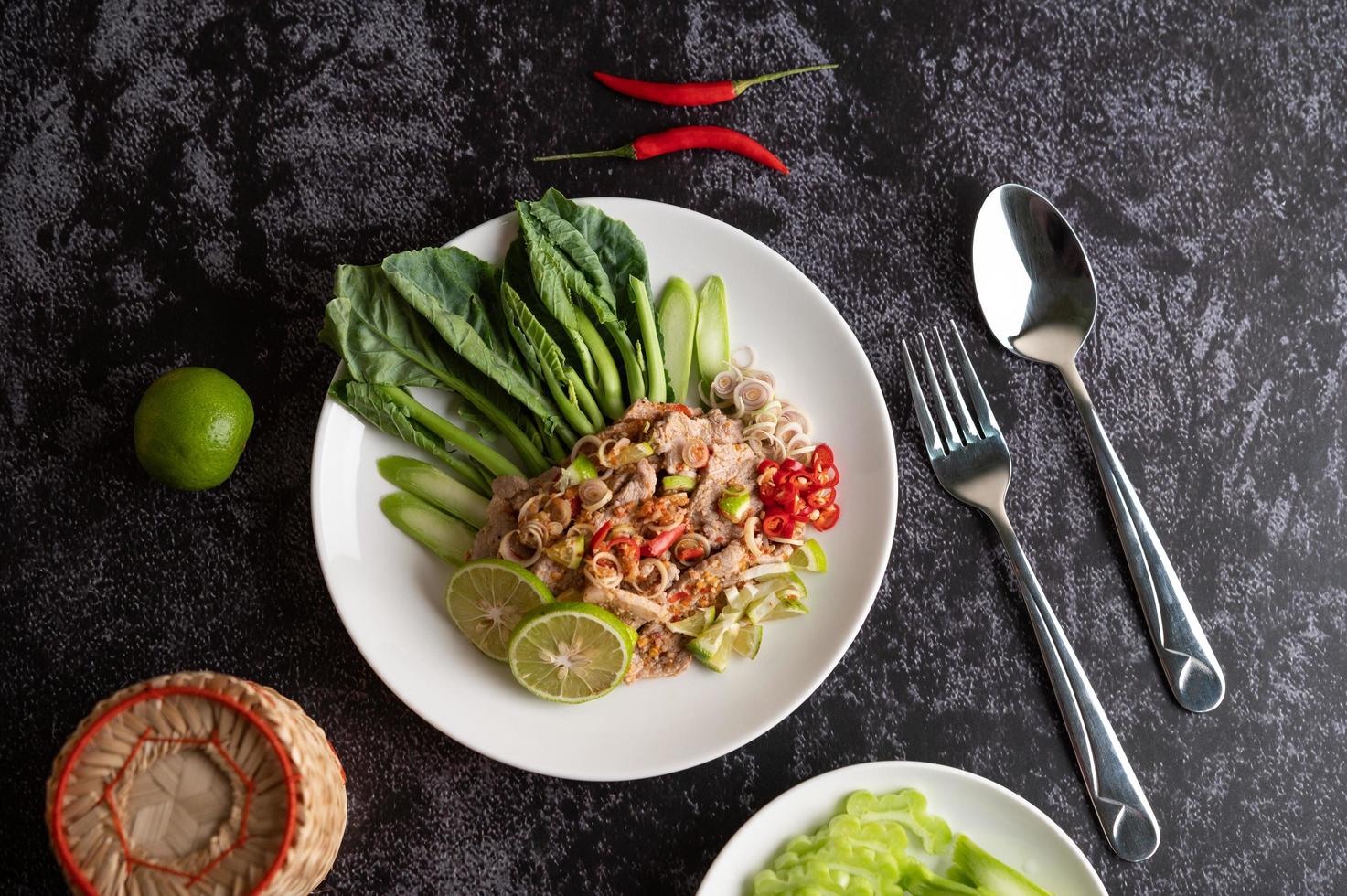 kryddig lime fläsk sallad med gröna och sidor foto