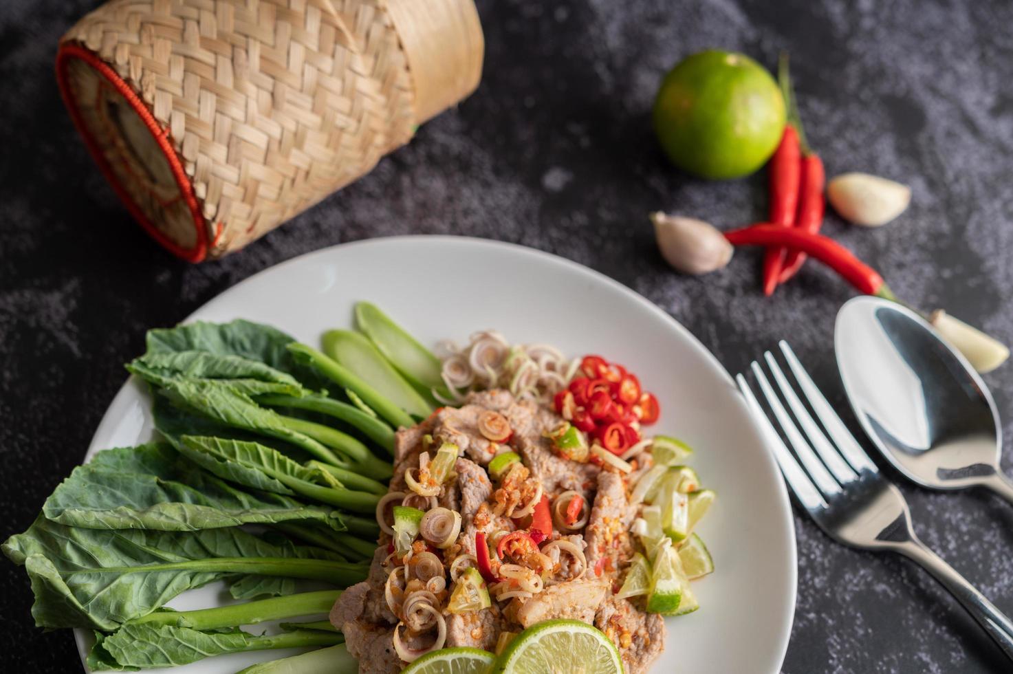 kryddig lime fläsk sallad med gröna och sidor foto