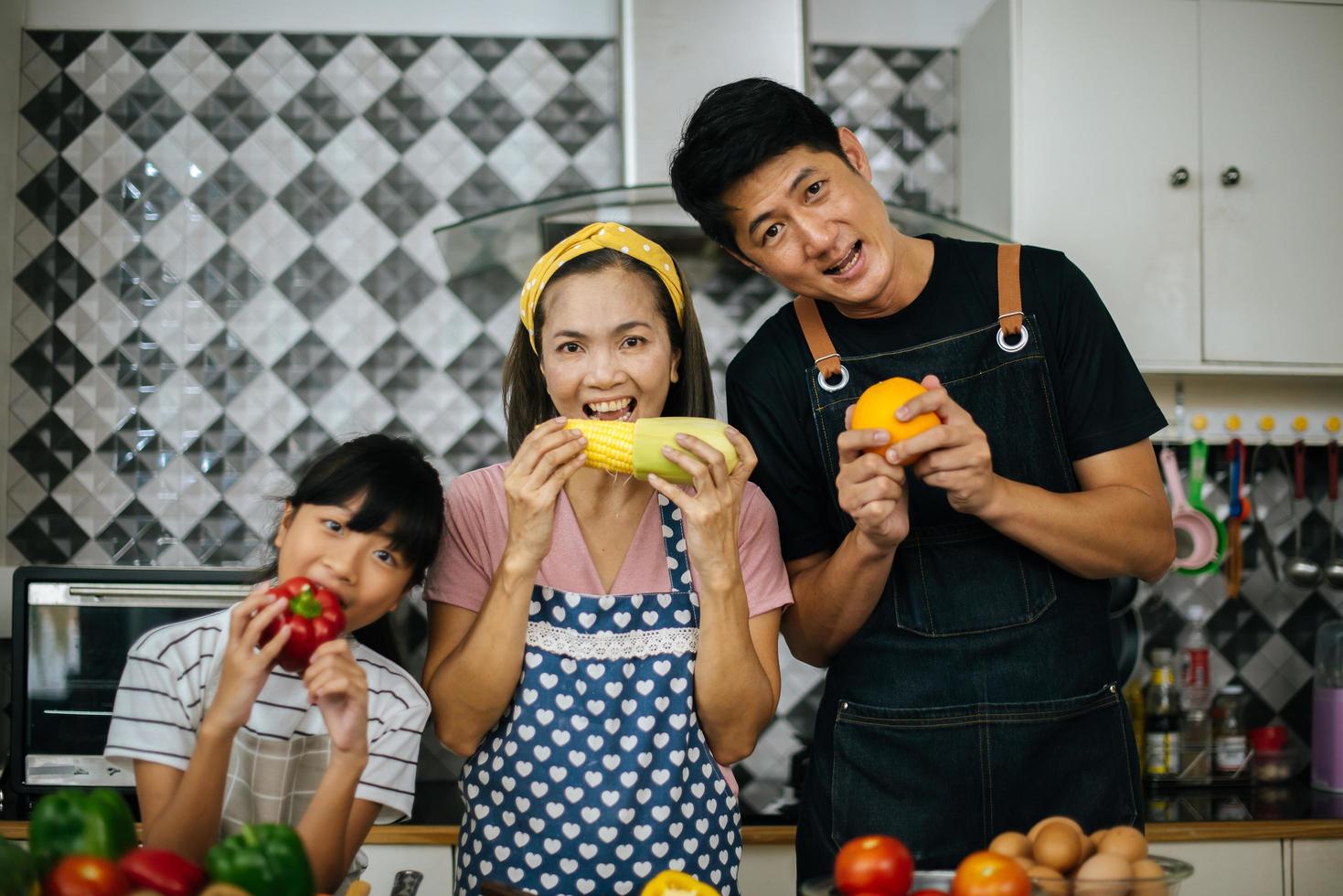 lycklig familj som skär grönsaker tillsammans i sitt kök foto