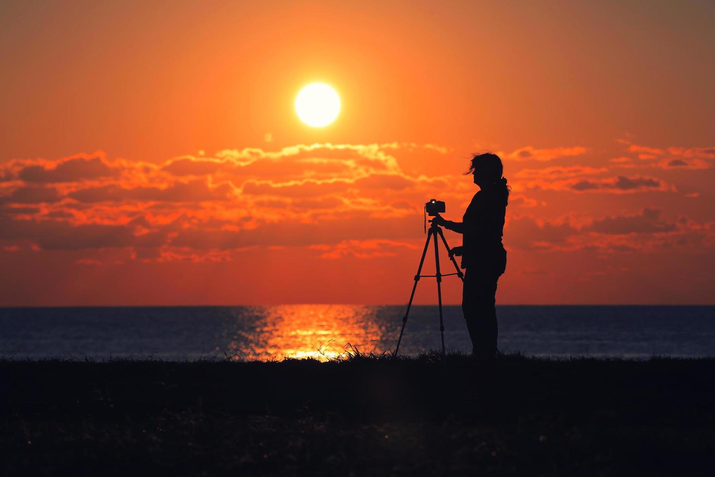 en fotografkvinna som tittar på solnedgången foto