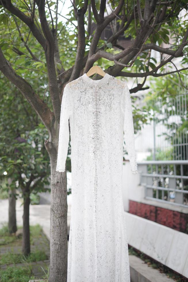 vit bröllop klänning hängande i träd för brud foto