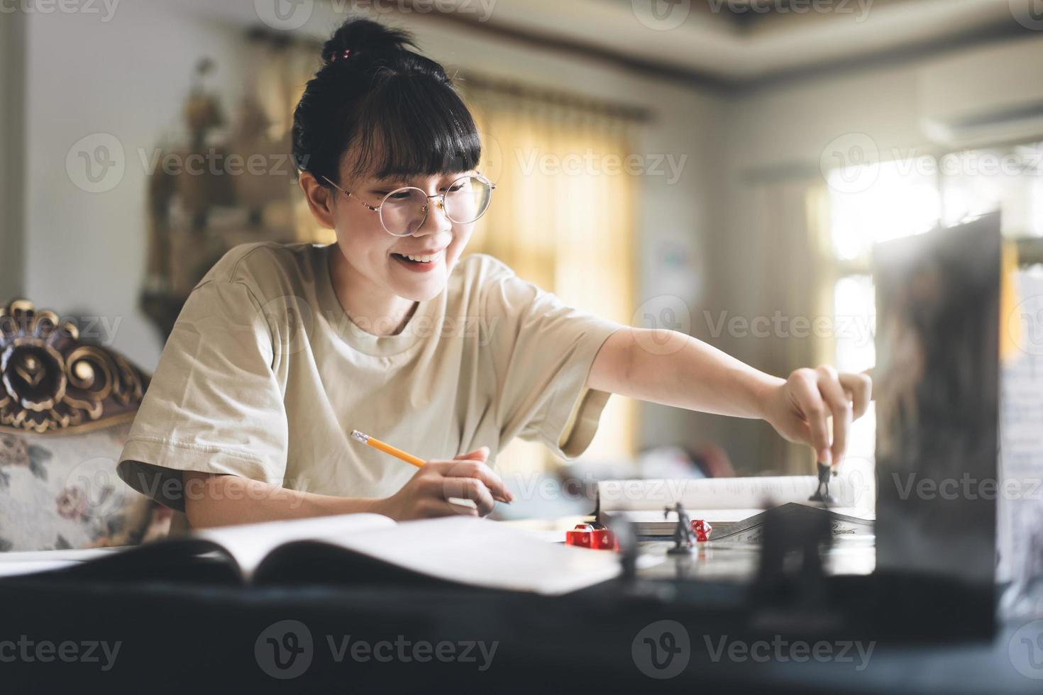 ung vuxen asiatisk kvinna njuter roll spelar bordsskiva berättande och styrelse spel med miniatyrer foto