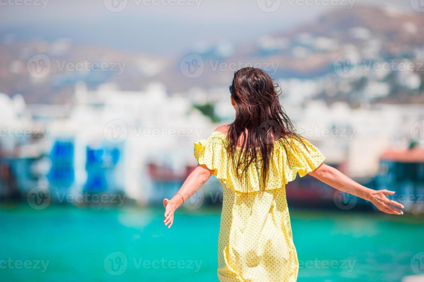 Lycklig ung kvinna på liten Venedig de mest populär turist område på mykonos ö, grekland. skön flicka njut av grekisk semester på liten Venedig bakgrund. foto