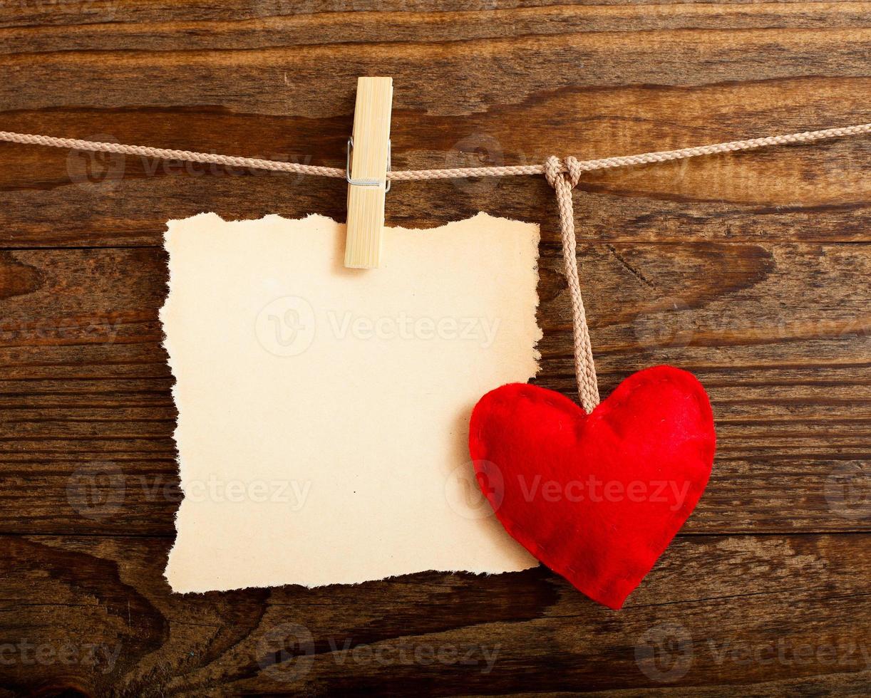 tom ark, en notera, en trasig ark av papper och årgång röd hjärta hängande på krans. valentines dag begrepp foto