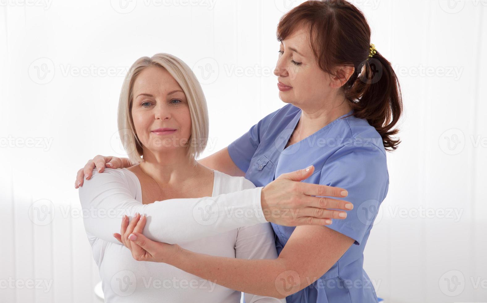 fysioterapeut arbetssätt med mitten åldrig patient i klinik foto