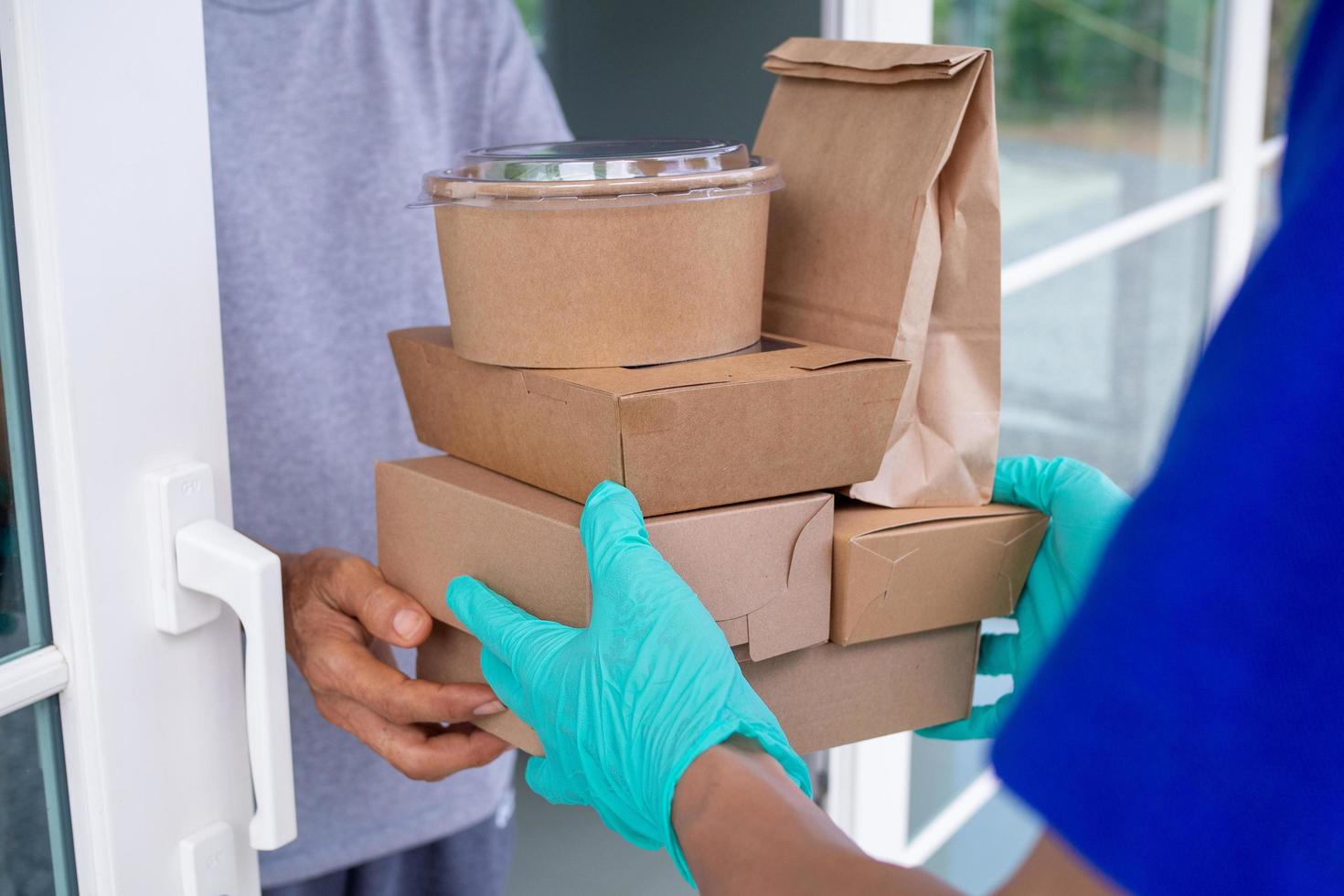 deliveryman bär en mask och handskar, leverans mat till de Hem av de uppkopplad köpare. stanna kvar på Hem minska de spridning av de covid-19 virus. de avsändare har en service till leverera Produkter eller mat snabbt foto