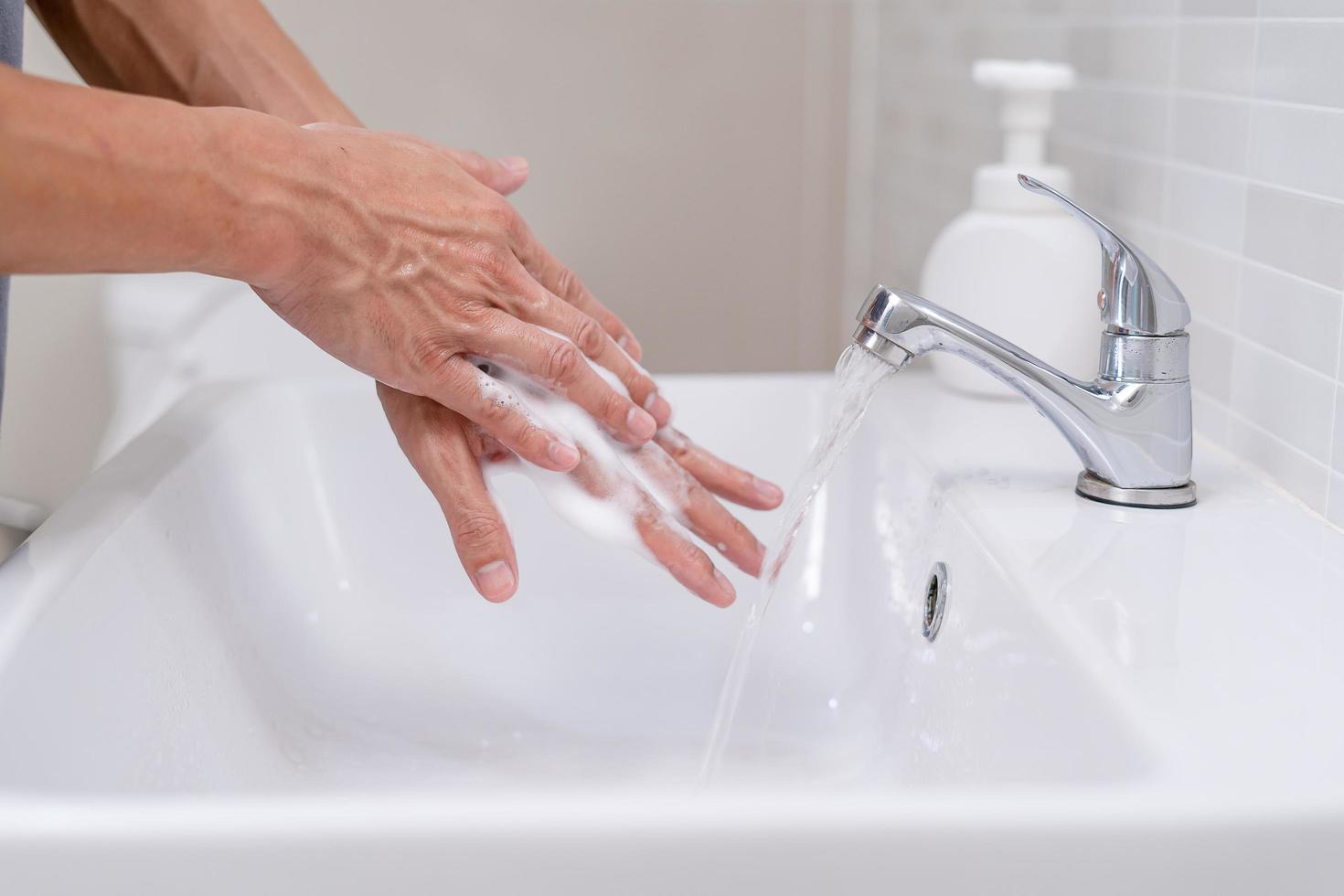 person händer tvätta med tvål bubblor och Skölj med rena vatten till förhindra och sluta de spridning av bakterier, virus eller covid19. Bra hälsa och Bra hygien foto