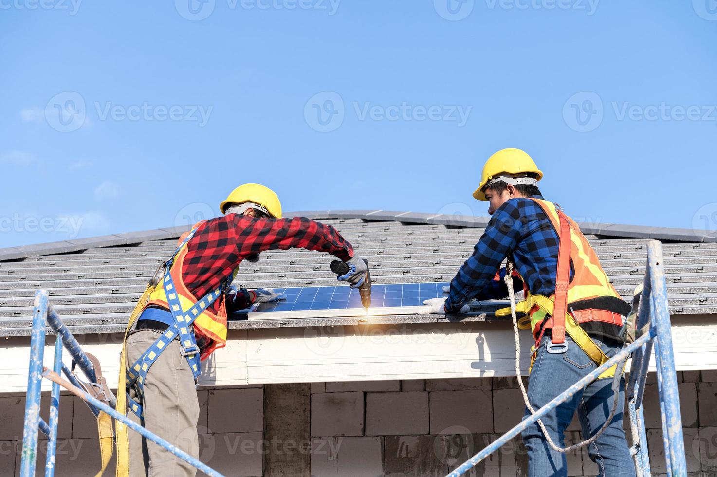 en team av asiatisk tekniker installerar sol- paneler på de tak av en hus. tvärsnitt se av byggare i hjälm montera sol- panel systemet begrepp av förnybar energi foto