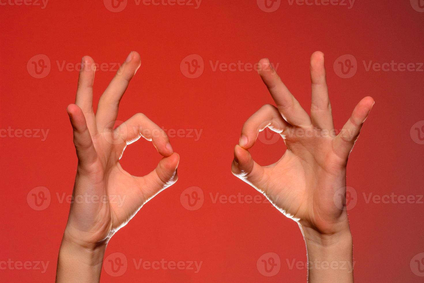 två mänsklig händer visa en tecken ok, isolerat på en röd bakgrund foto