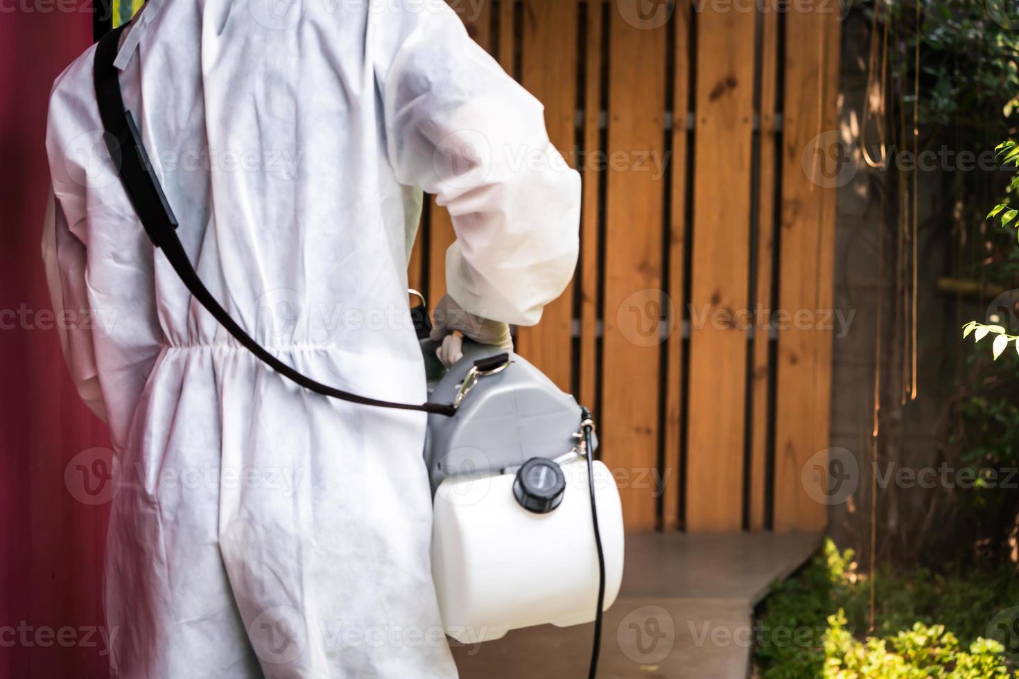 professionell teknisk man i förebyggande kostym med hans sterilisering maskin och desinficerande vatten sprayer i de utomhus- fält för renande coronavirus foto