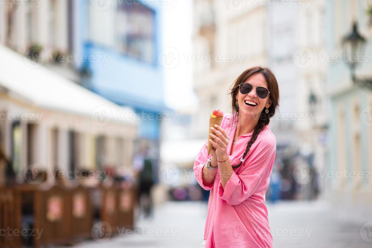 ung kvinna modell äter is grädde kon utomhus. sommar begrepp - kvinna med ljuv glass på varm dag foto