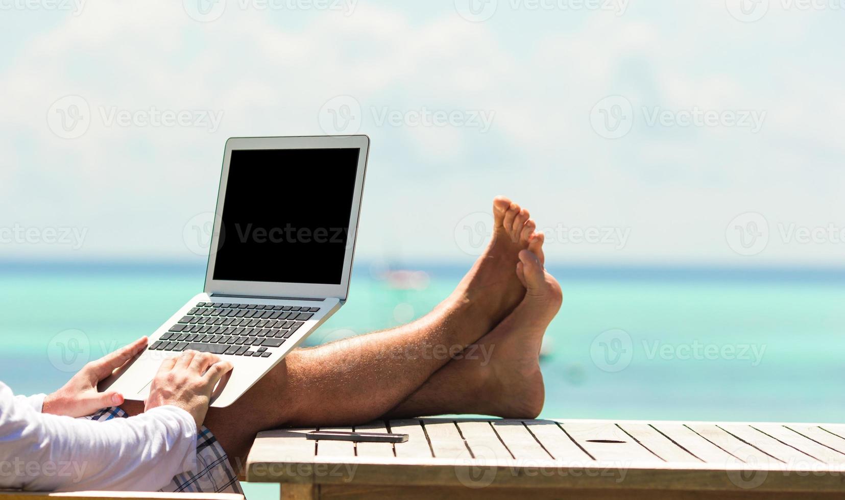 ung man med läsplatta dator under tropisk strand semester foto