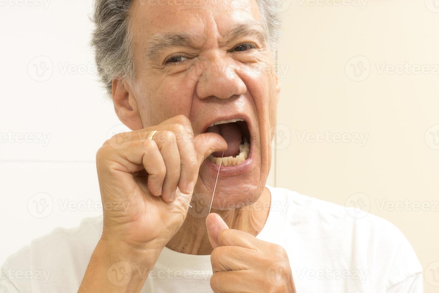 senior man tandtråd hans tänder med dental flock foto