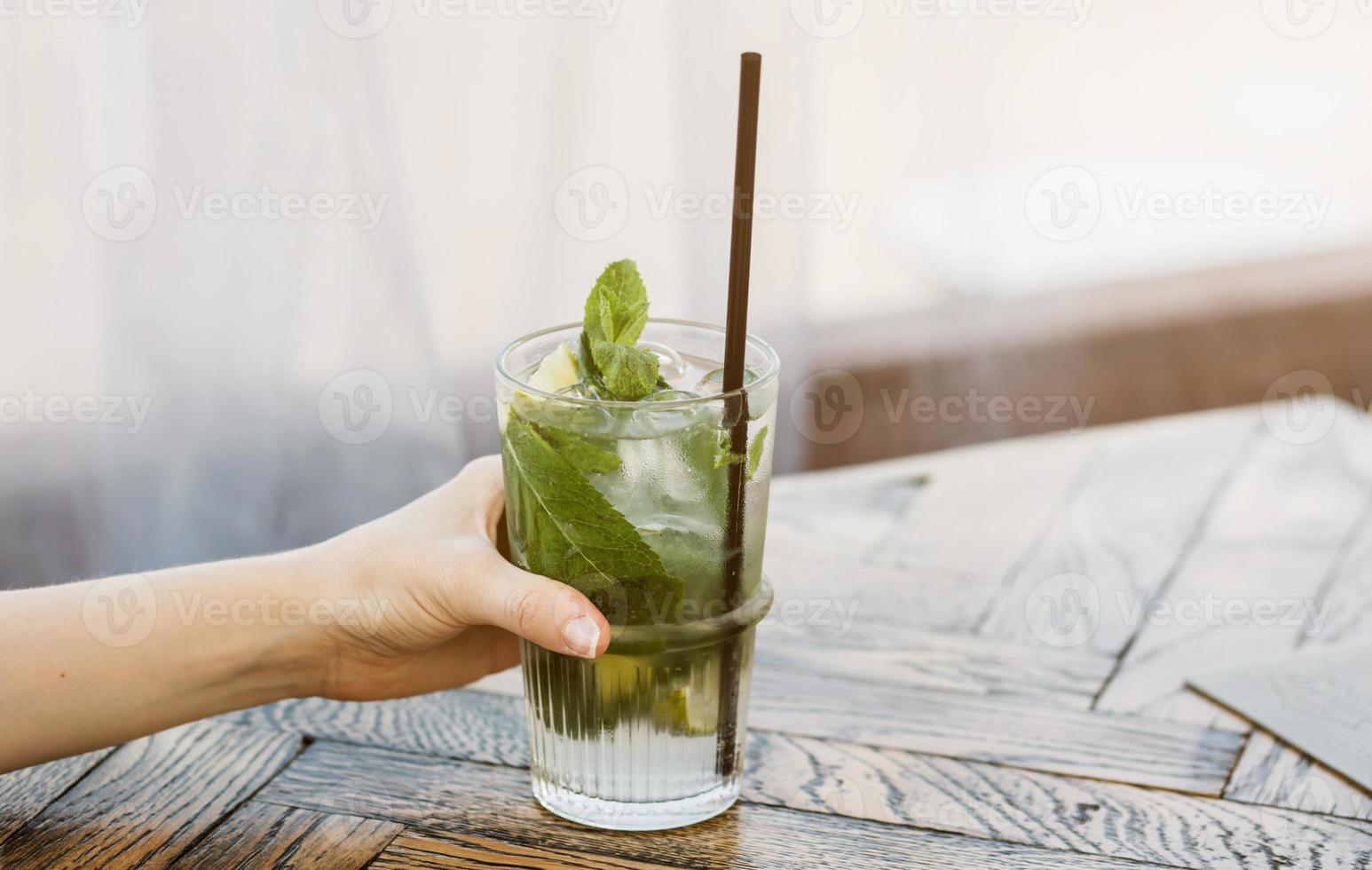 hand innehar en mojito med is foto