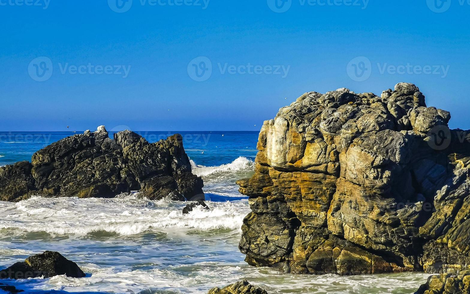 skön stenar klippor surfare vågor på strand puerto escondido Mexiko. foto