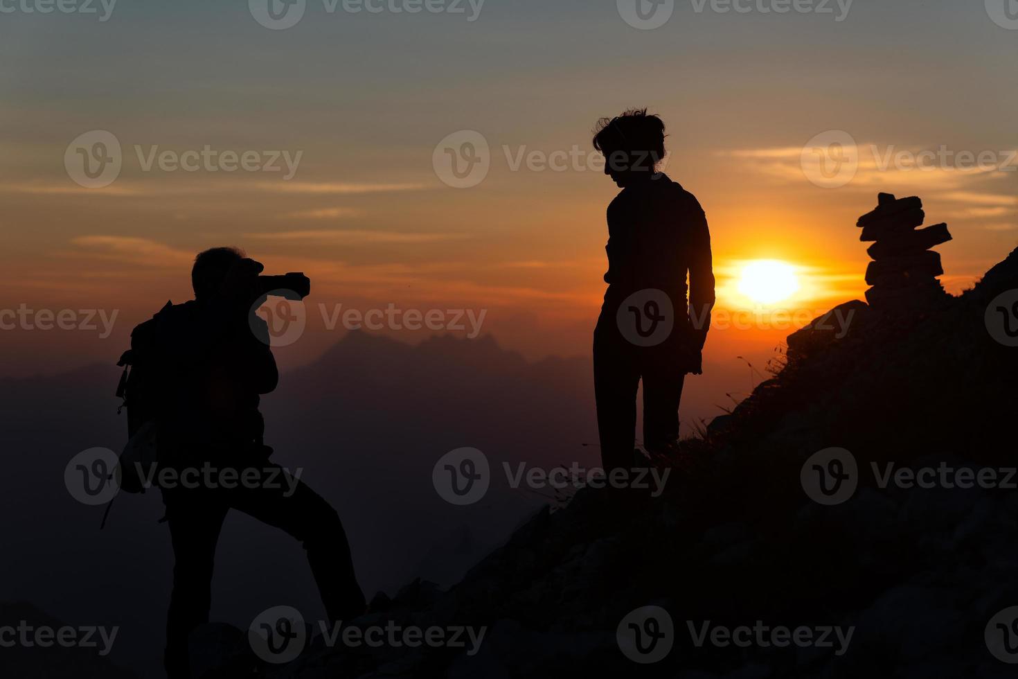 fotograf utför fotografi till en flicka på solnedgång i hög bergen i silhuetter foto