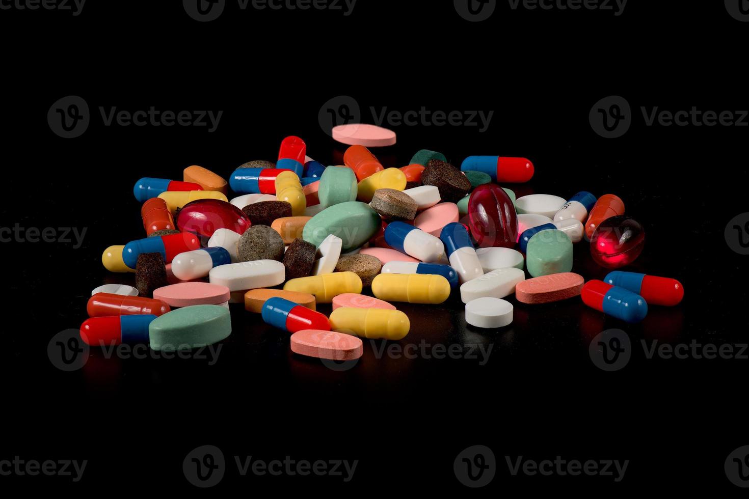mediciner i kapslar av många färger på en svart bakgrund foto