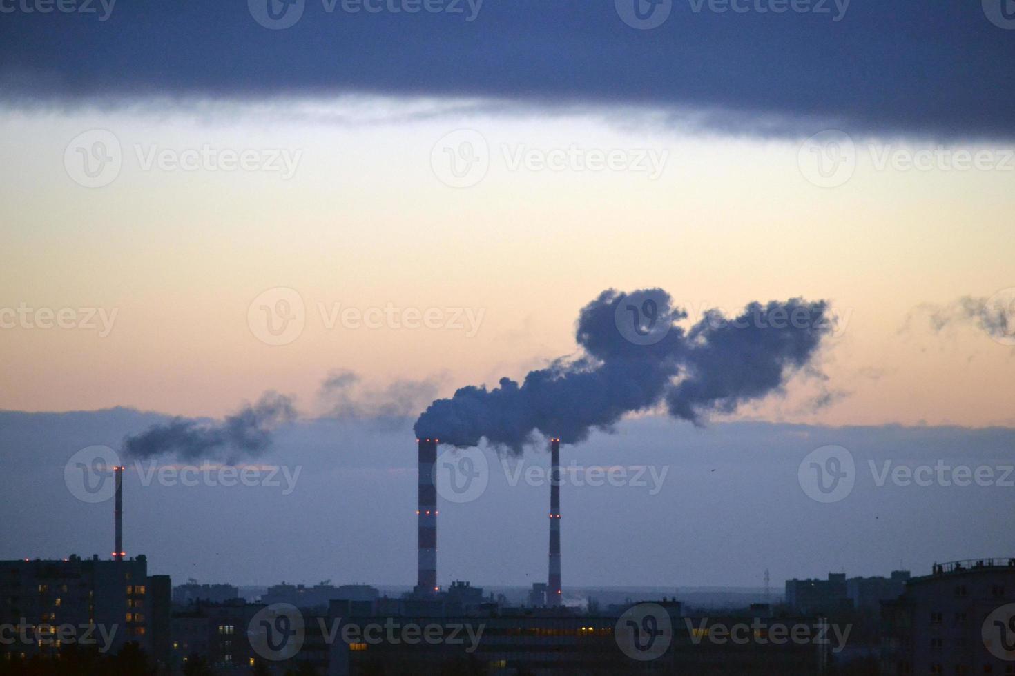 rök kommande från fabrik skorsten på solnedgång foto