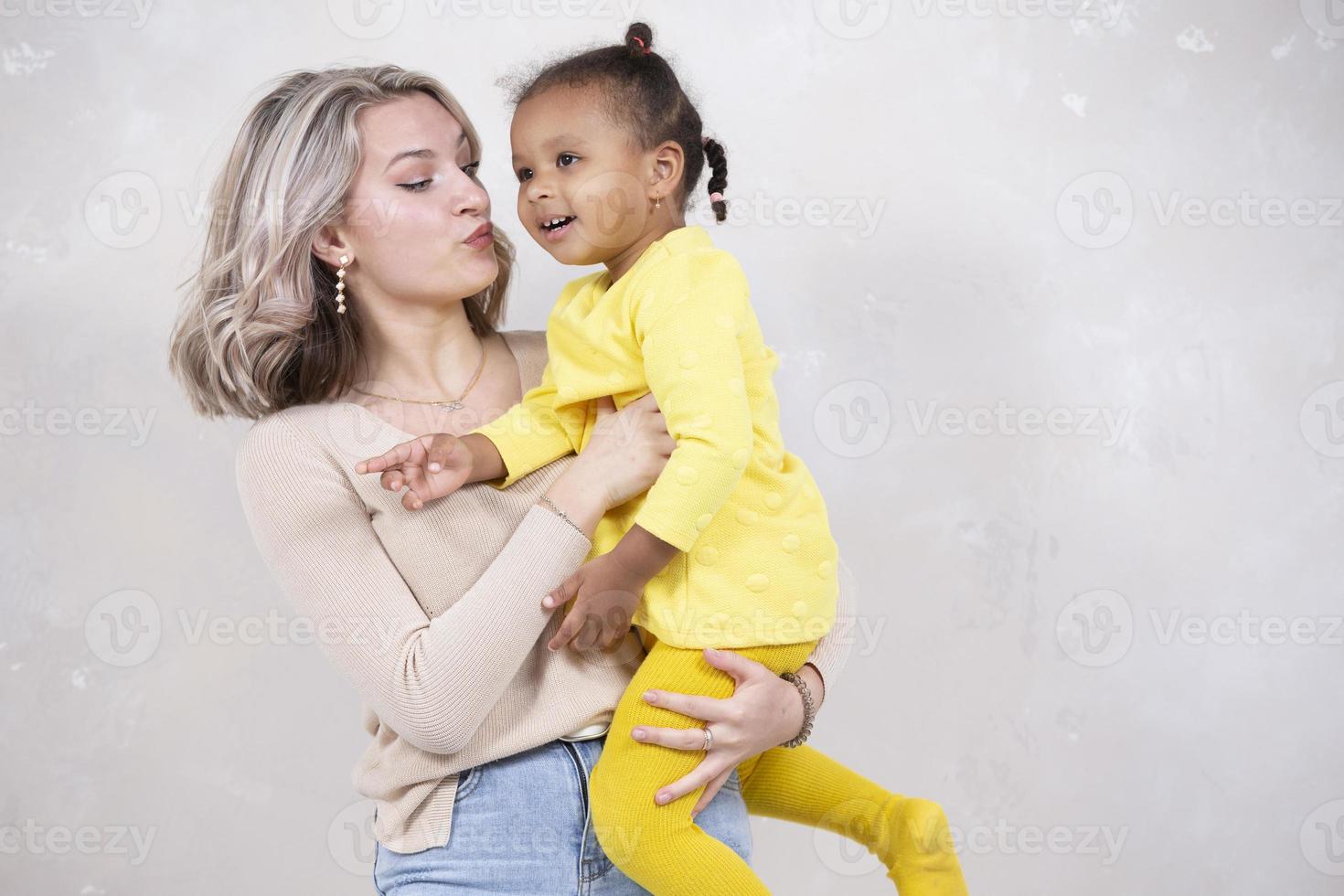 multietnisk mamma och dotter spela på Hem. glad mor med liten dotter av afrikansk nationalitet. familj från annorlunda lopp. foto