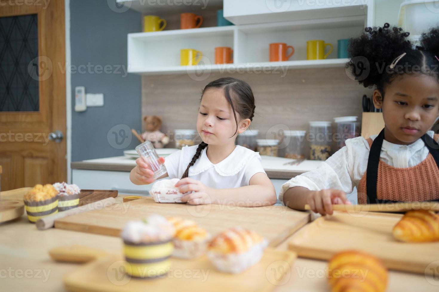 två Lycklig liten barn syskon matlagning tillsammans, rullande ut deg, stående på trä- bänkskivan i modern kök, söt hemlagad foto