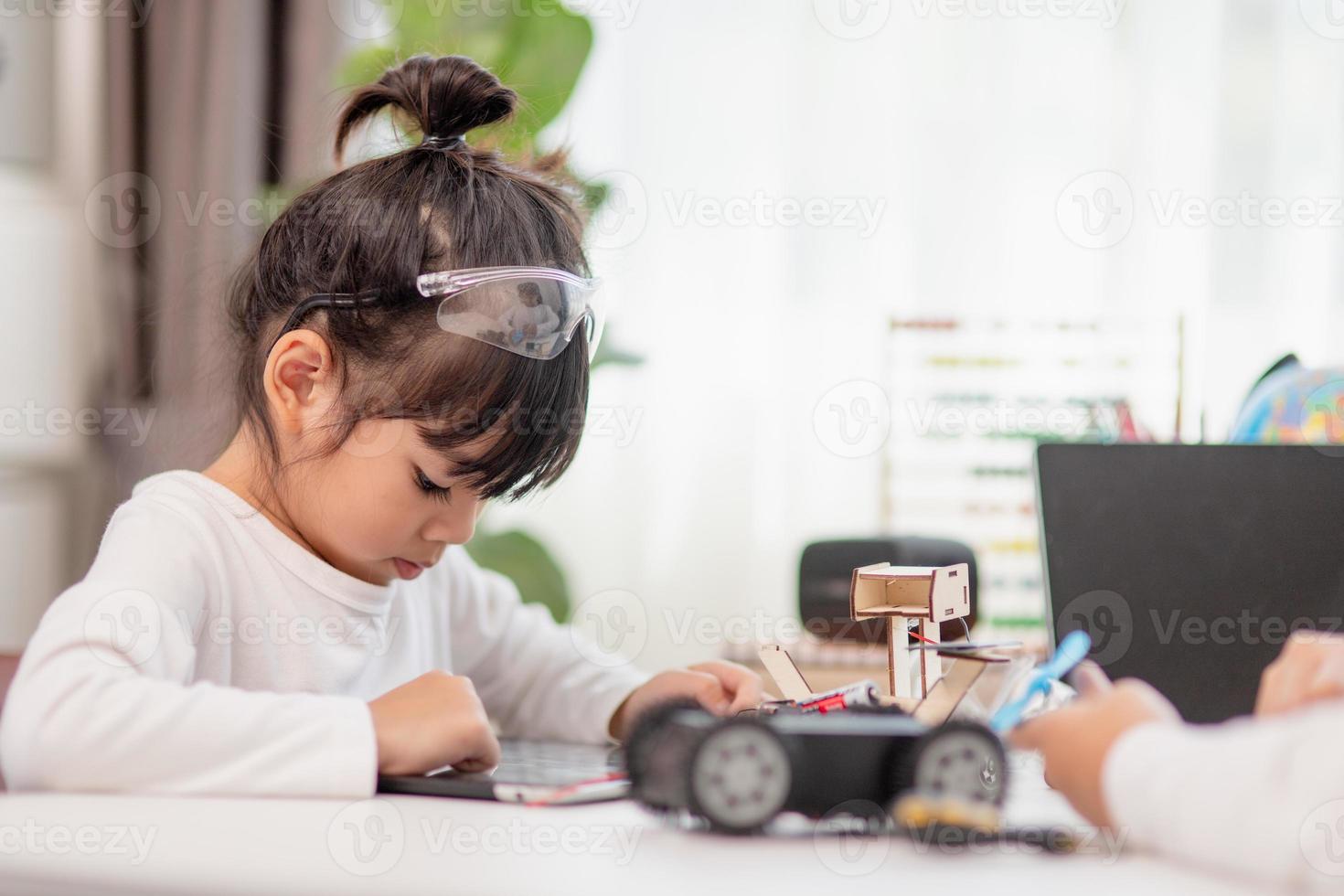 Asien-studenter lär sig hemma i kodning av robotbilar och kablar för elektronikkort i stam, steam, matematik ingenjör vetenskapsteknik datorkod i robotik för barn-koncept. foto