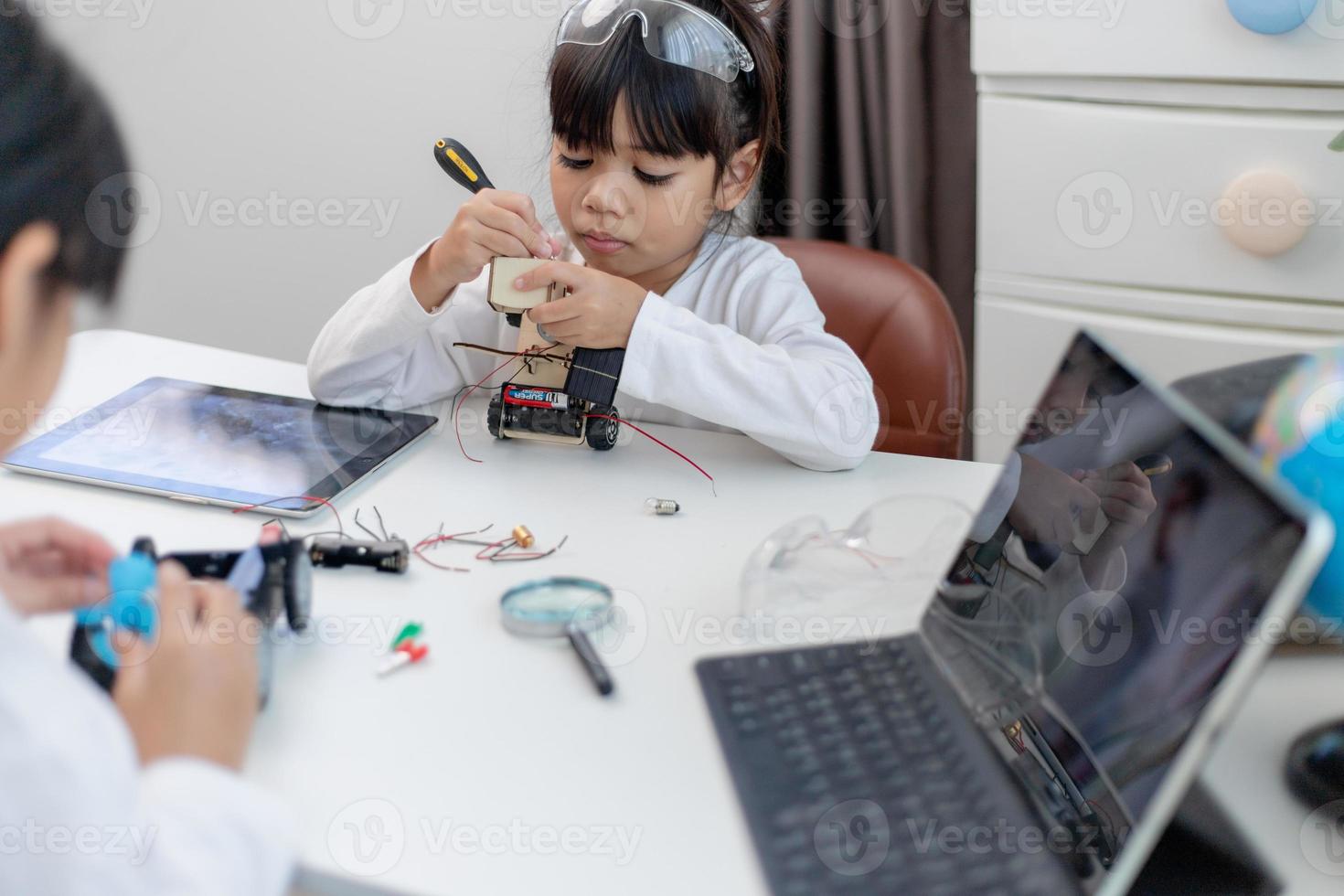 Asien-studenter lär sig hemma i kodning av robotbilar och kablar för elektronikkort i stam, steam, matematik ingenjör vetenskapsteknik datorkod i robotik för barn-koncept. foto