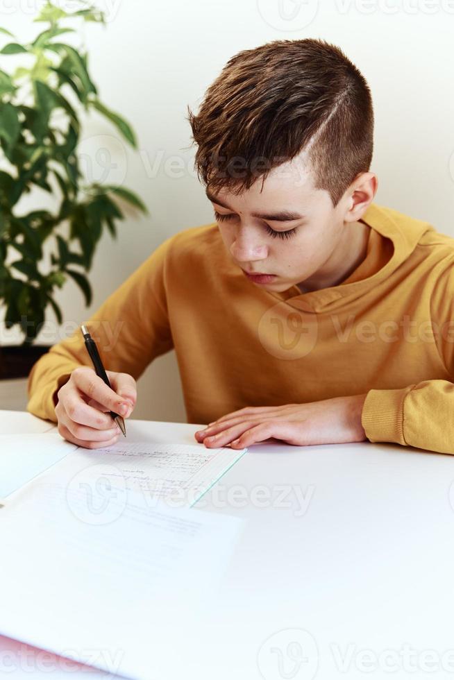Tonårs pojke skriva läxa på Hem. utbildning begrepp foto