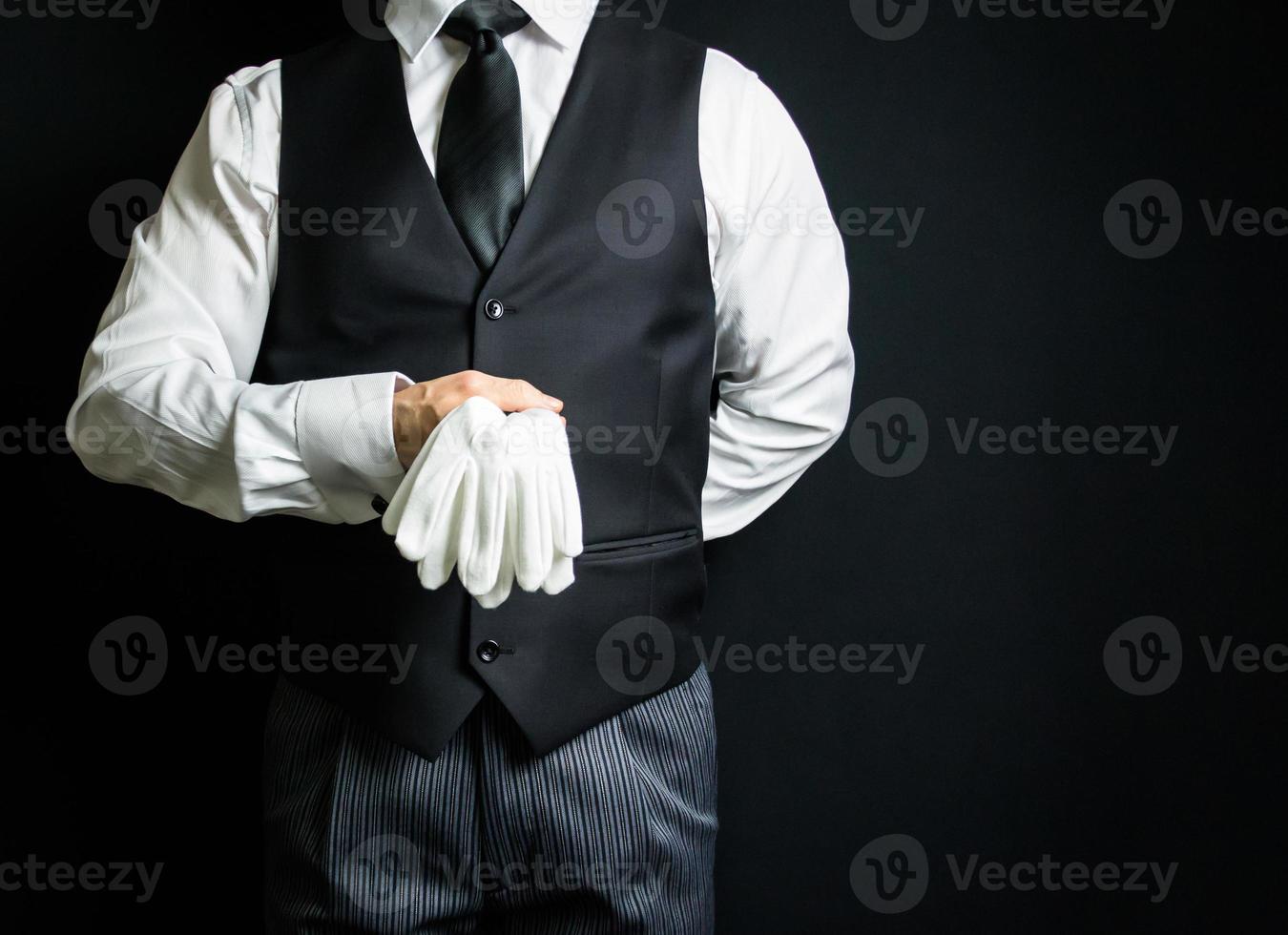 porträtt av butler i mörk kostym innehav rena vit handskar. kopia Plats för service industri och professionell artighet. foto